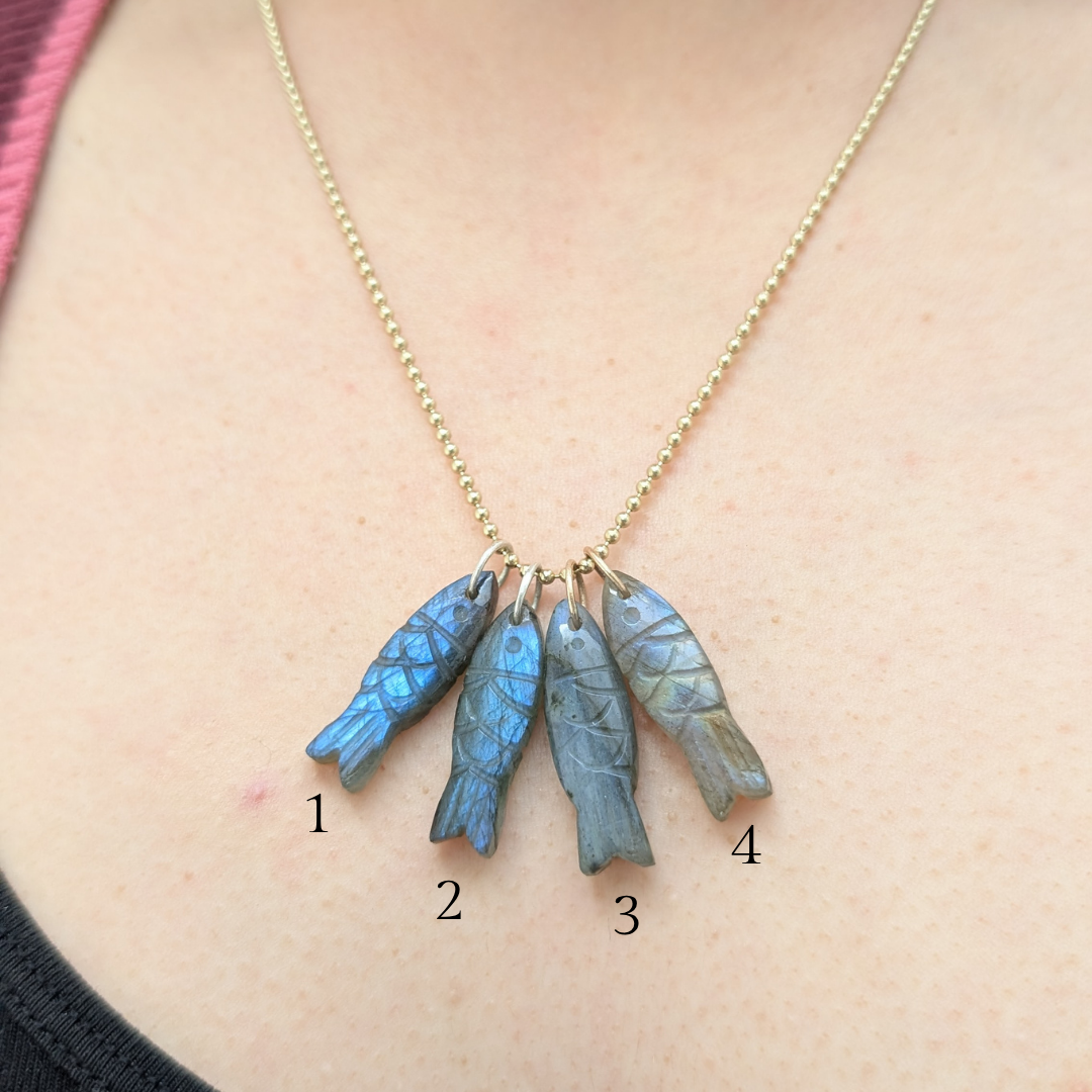 Necklace with 4 fish pendants, worn by a person