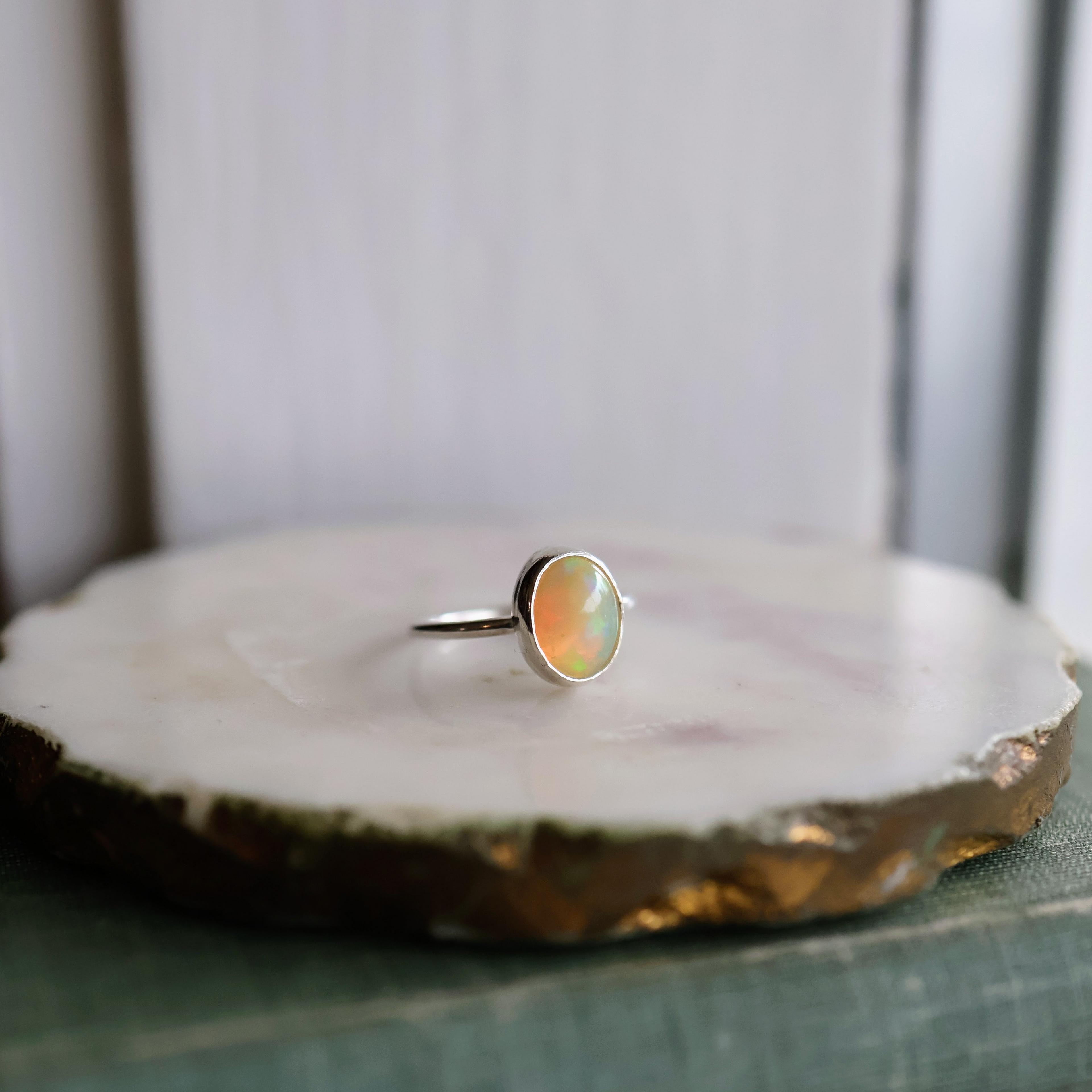 Opal and sterling silver ring on a marble surface with a blurred background