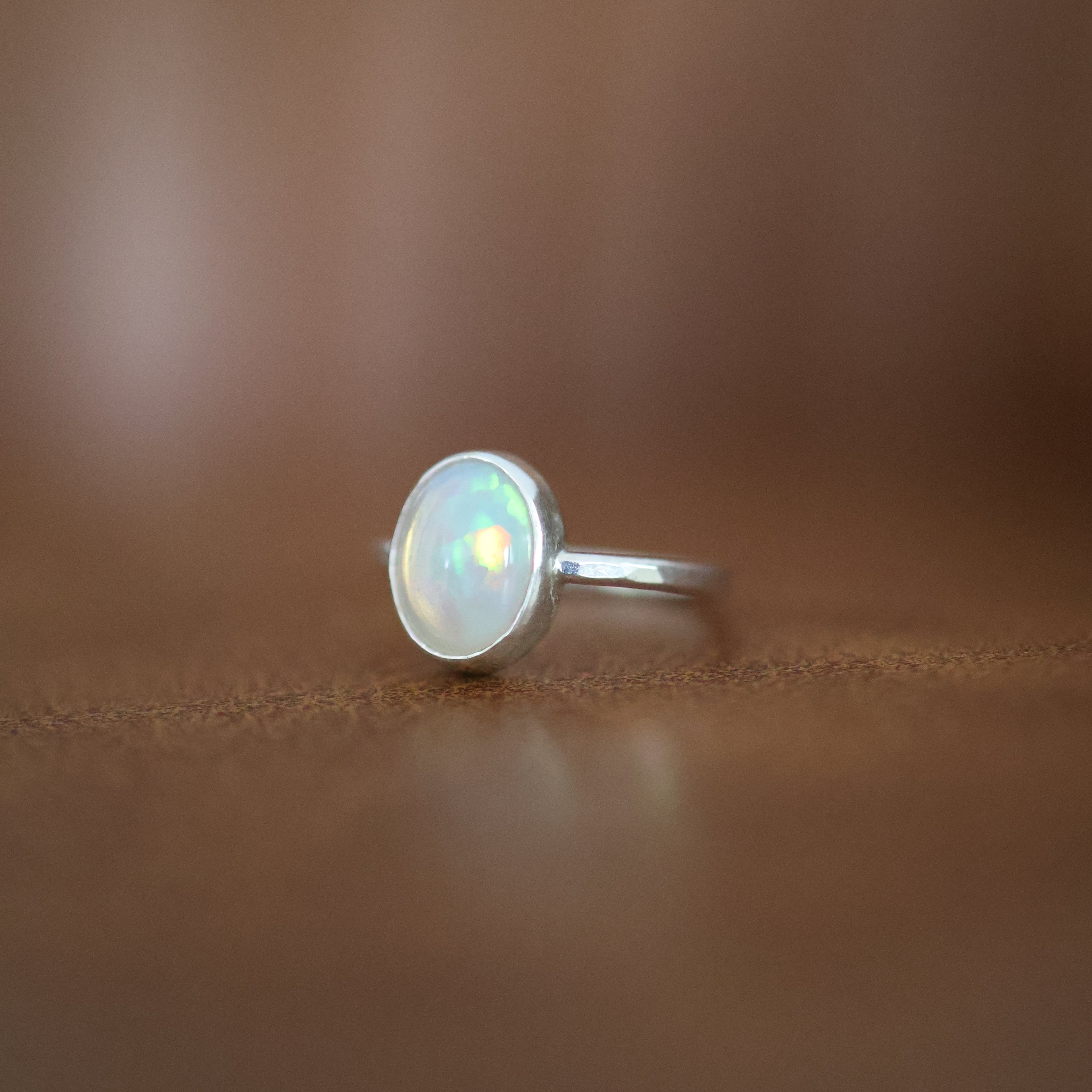 Silver ring with an oval Ethiopian opal on a brown surface