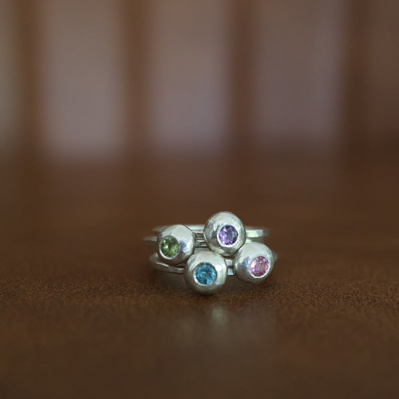 a stack of 4 gemstone rings on a brown background