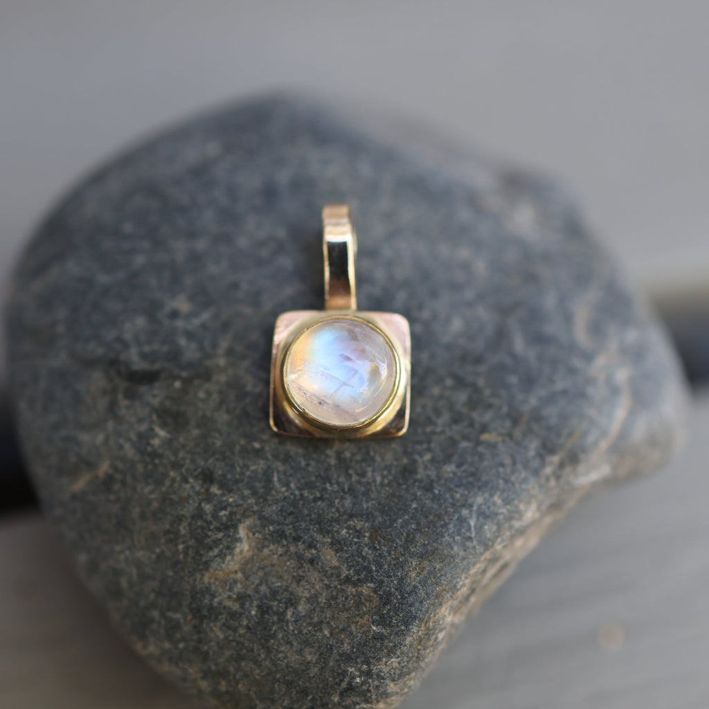 Gold pendant with a moonstone on a rock