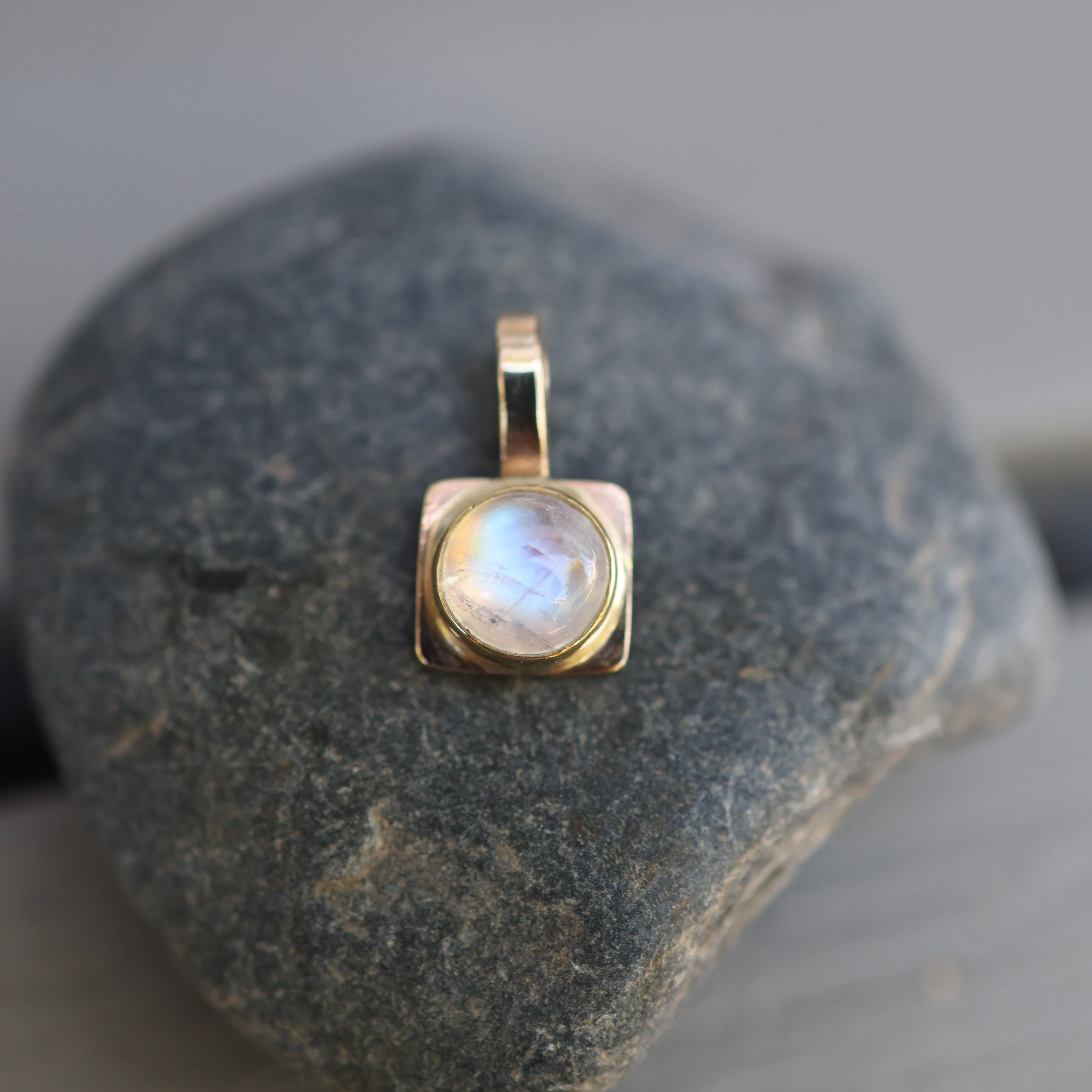 Gold pendant with a moonstone on a rock