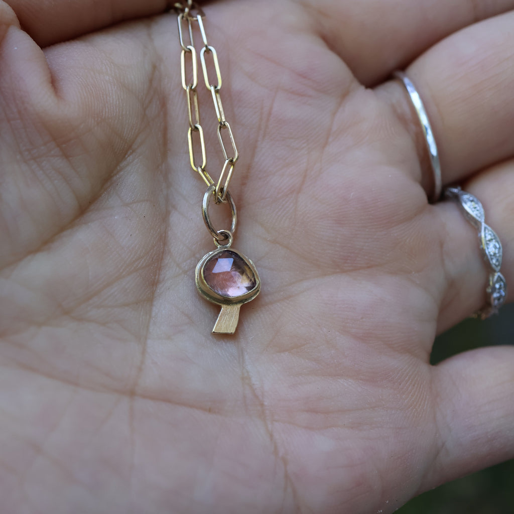 Gold necklace with a pink gemstone on a hand