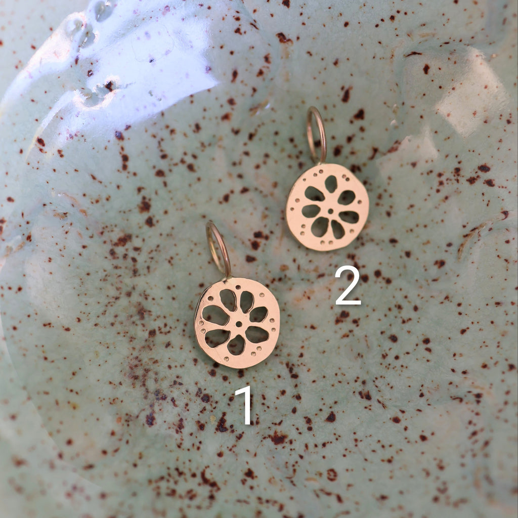 Two gold lotus root shaped pendants on a textured green background
