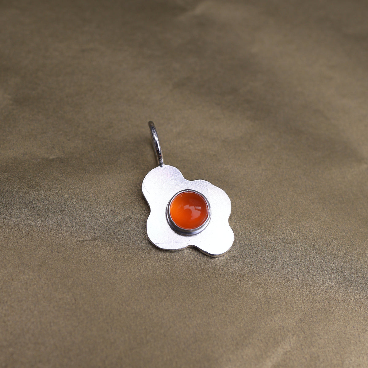 a pendant in the shape of a sunny side up fried egg with a orange center stone