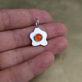 a pendant in the shape of a sunny side up fried egg with a orange center stone