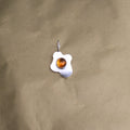 a pendant in the shape of a sunny side up fried egg with a orange center gemstone