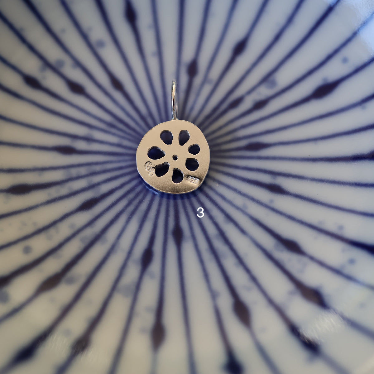 back of a silver lotus root charm showing quality and maker's mark stamps
