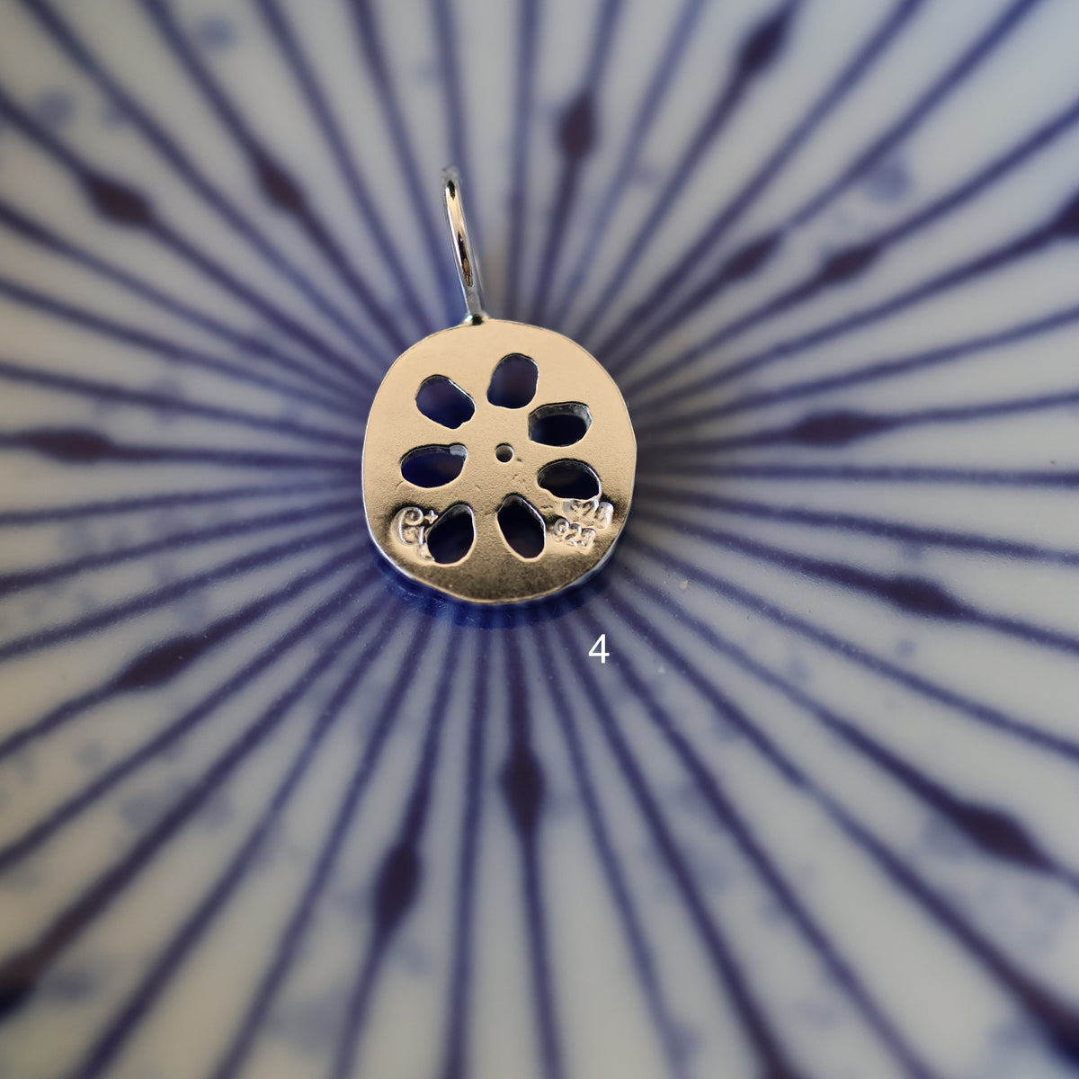 back of a silver lotus root charm labeled '4' showing maker's mark and sterling silver quality stamp