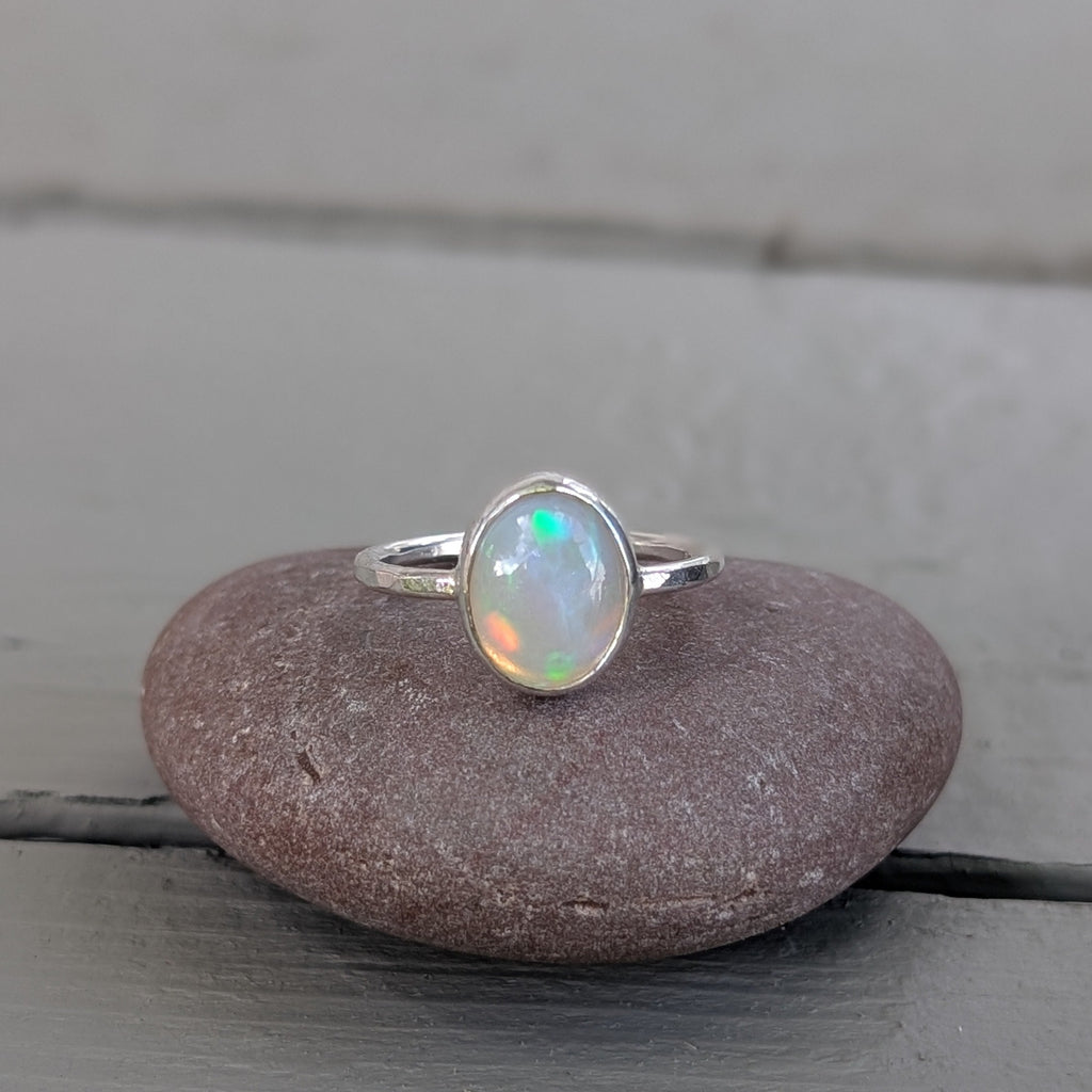 Opal ring on a pebble with a wooden background