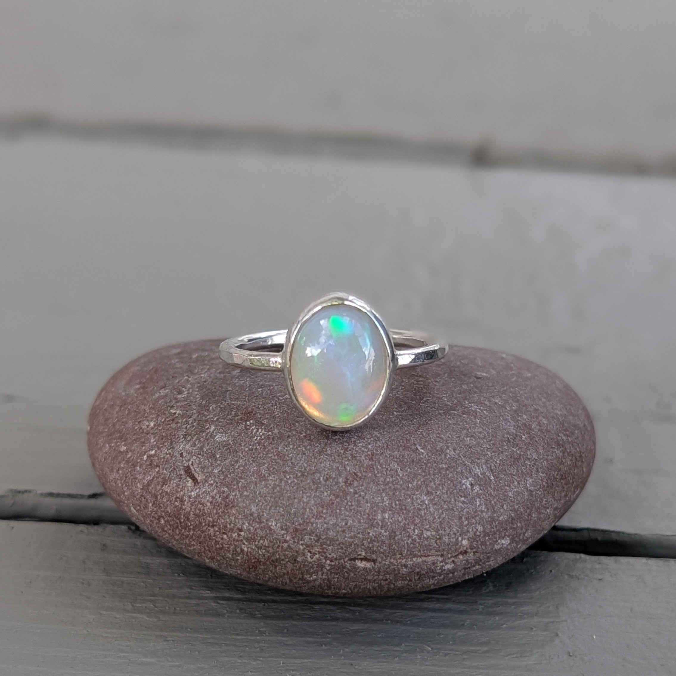 Opal ring on a pebble with a wooden background