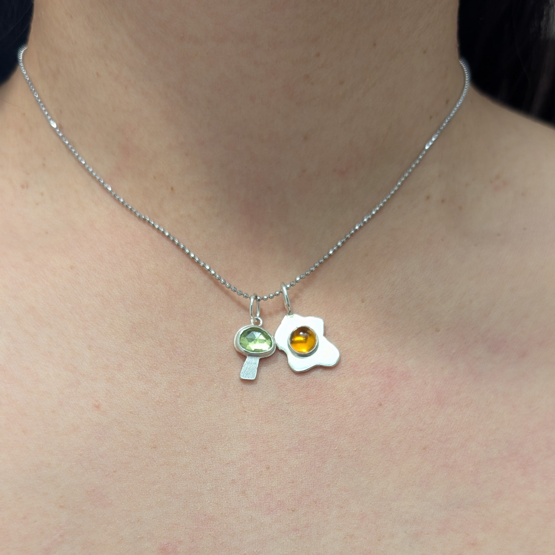 Necklace with a mushroom and egg pendant worn by a person