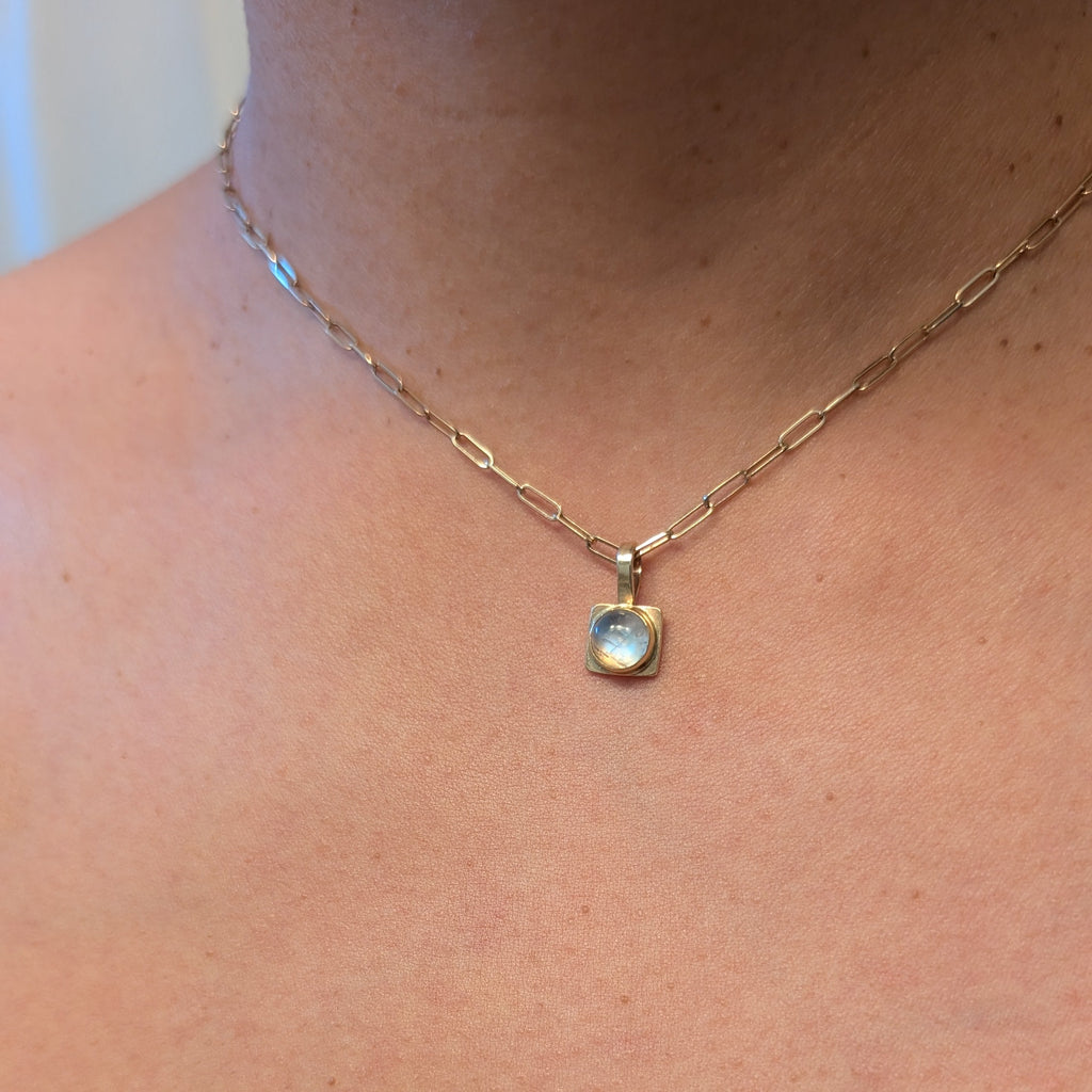Necklace with a pendant worn by a person, focusing on the necklace.
