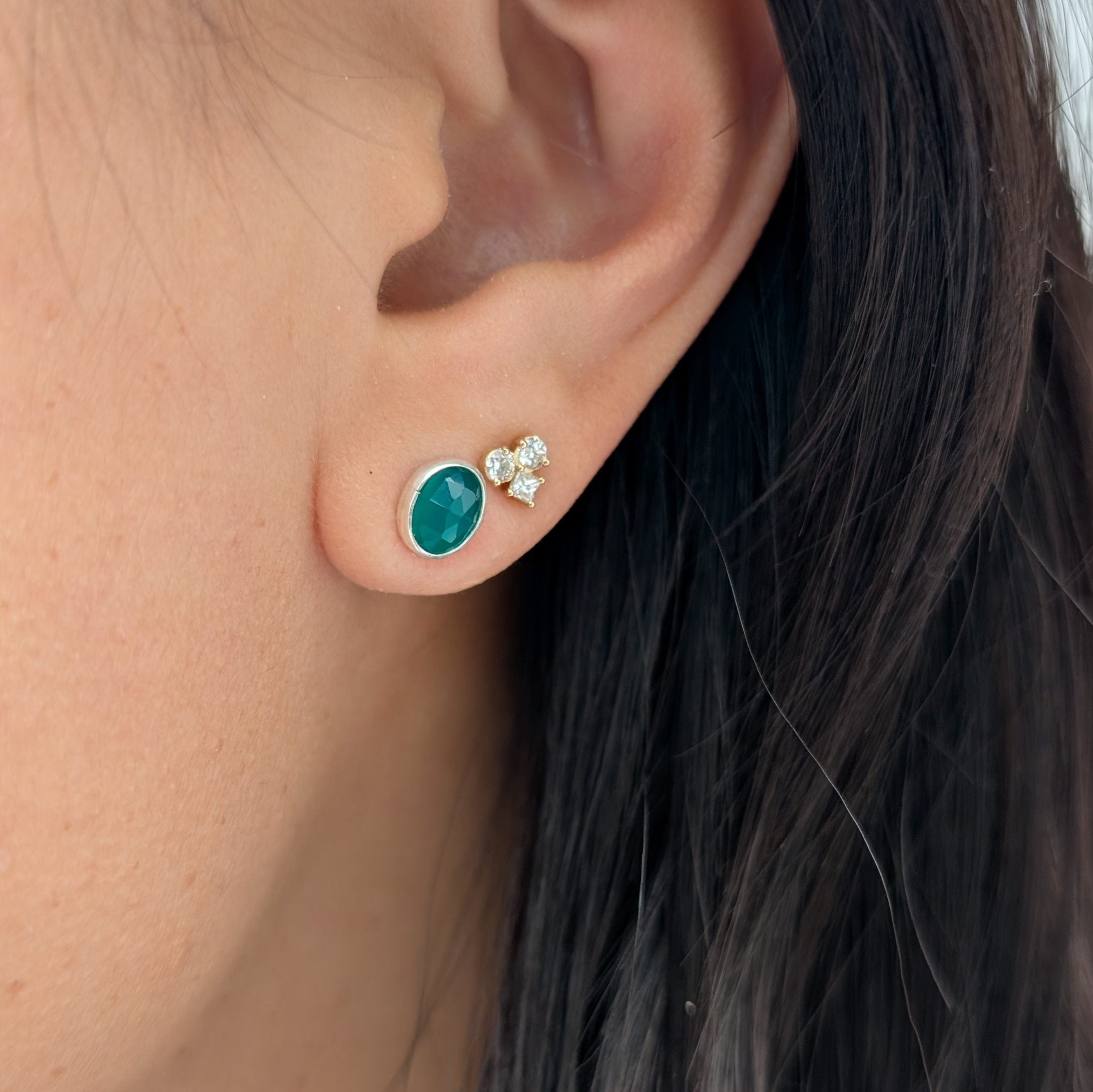 Close-up of an ear wearing a green onyx earring.