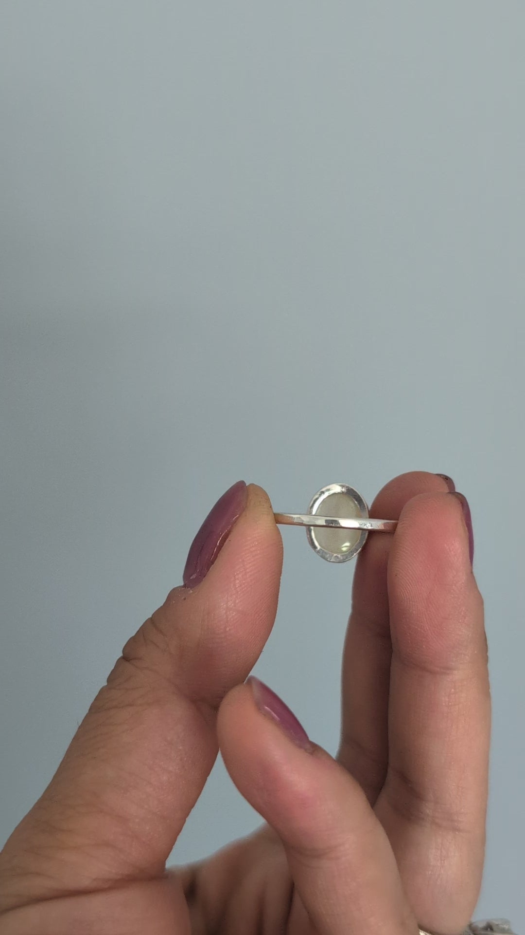 Hand holding a ring with a colorful Ethiopian opal